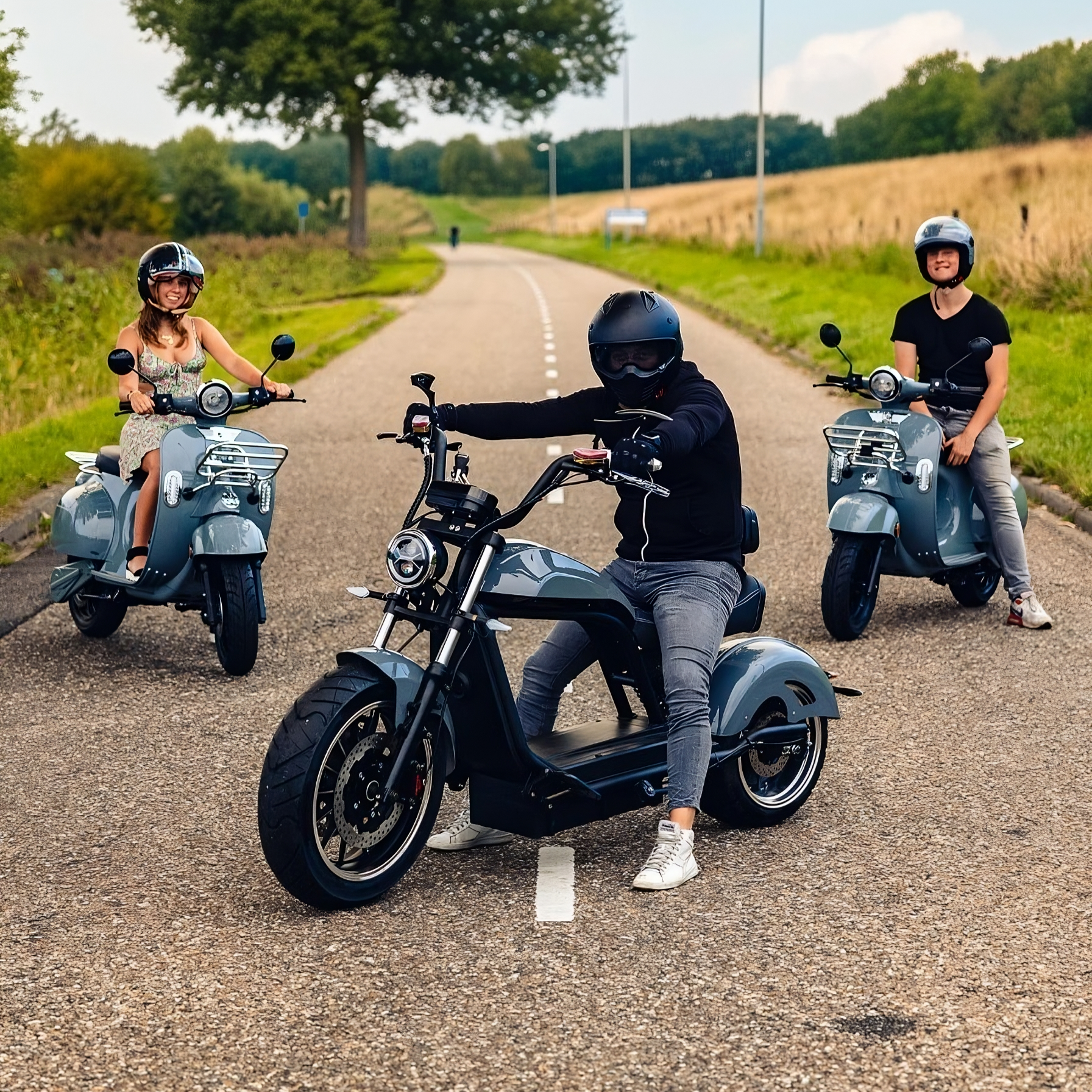 Ein Fahrer sitzt entspannt auf einem nardograuen Star-Biker Chopper 6.0s, während zwei Personen jeweils auf einem Shelwy Italian E-Roller durch die Stadt cruisen – leise, umweltfreundlich und stilvoll unterwegs.