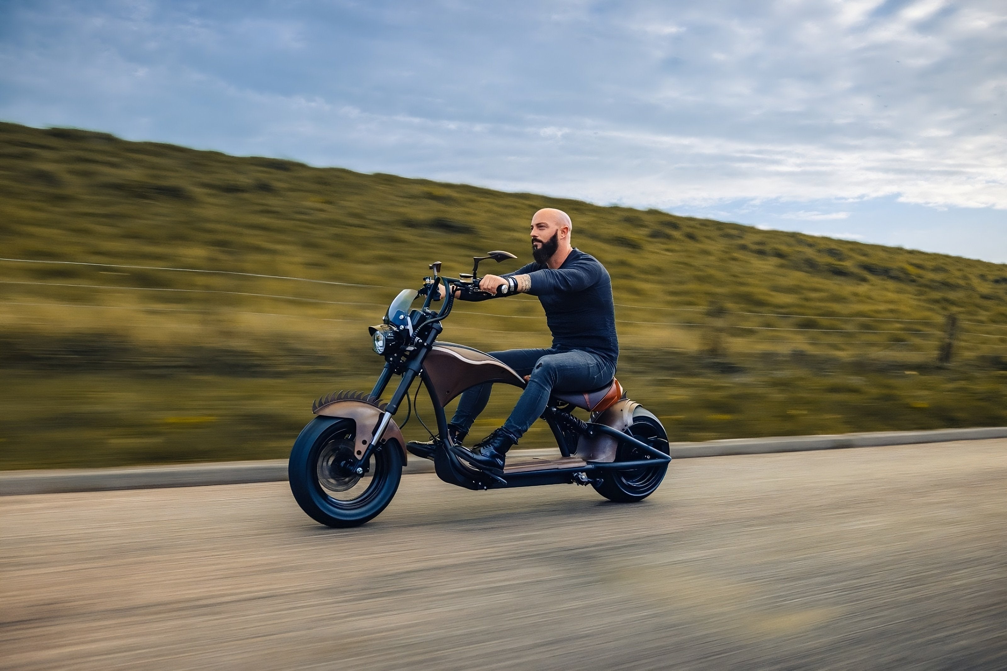 Person fährt mit einem Star-Biker E-Chopper entspannt über eine grüne, von Bäumen gesäumte Landstraße – symbolisch für umweltfreundliche Elektromobilität und nachhaltigen Fahrspaß.