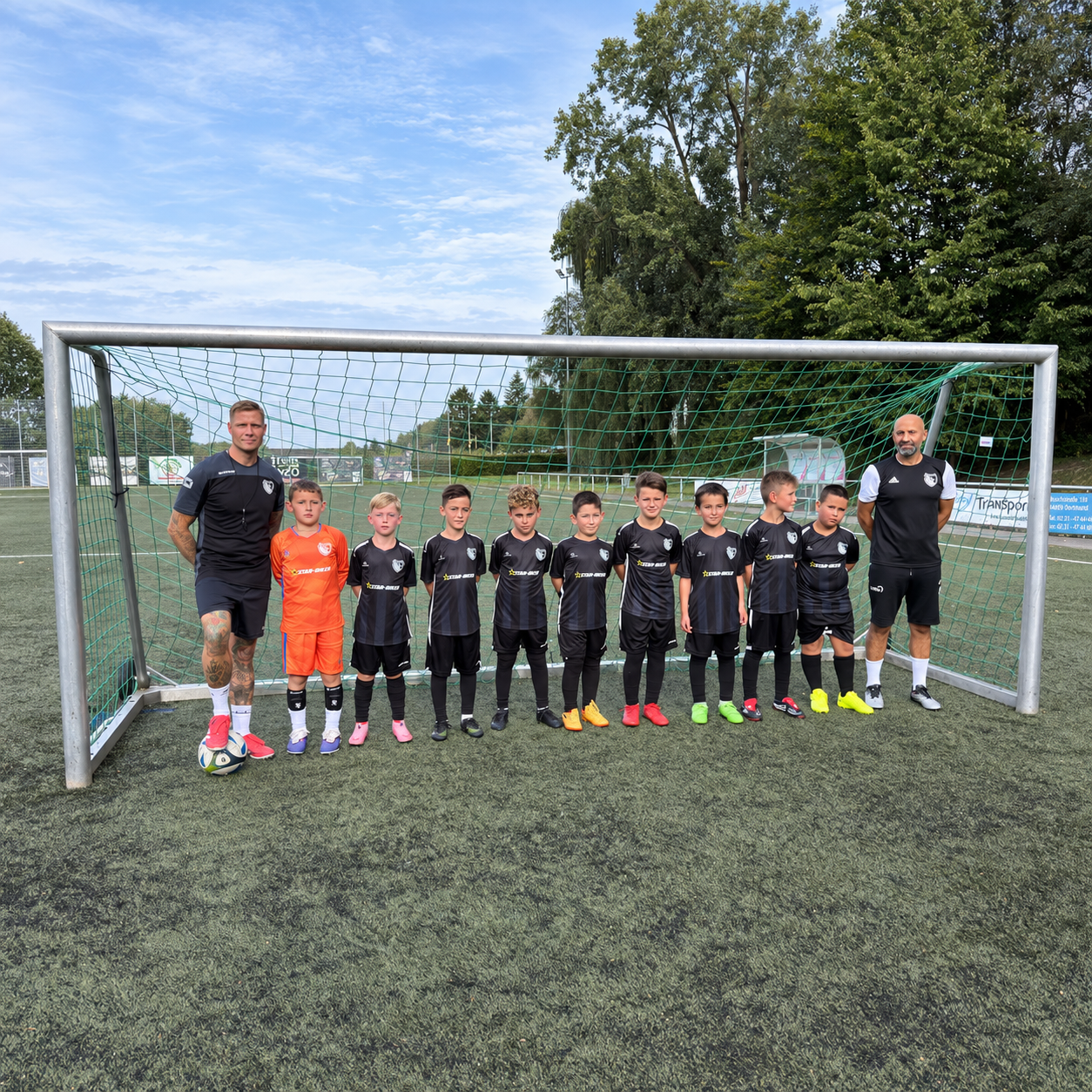 Jugendmannschaft des TuS Rahm 16/60 in Dortmund mit neuen Star-Biker Trikots vor dem Fußballtor.